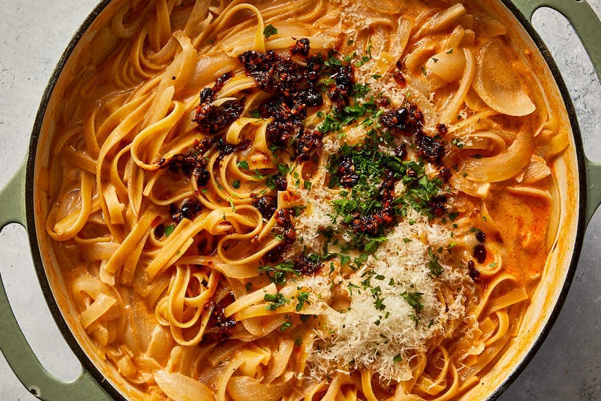 adding chili oil to the cooked pasta