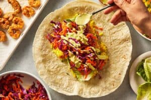 Hand drizzling salsa verde into the tortilla