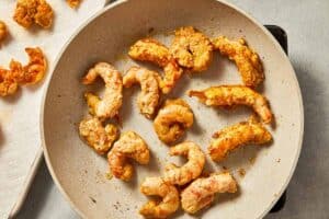 Seasoned shrimp cooking in a large non-stick skillet.