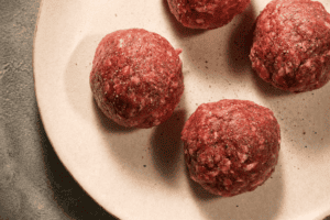 Raw meatballs on a white plate